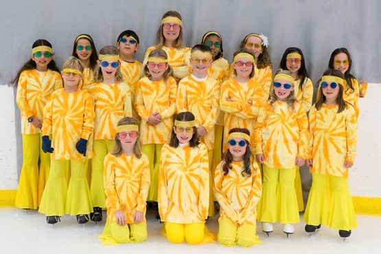 Ice skaters in yellow costumes posing for a photo
