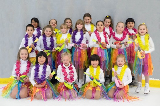 Child ice skaters in colorful costumes posing for a photo.